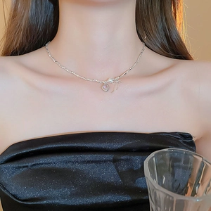 Detailed view of silver pearl necklace with bow and heart pendant on a model in sunset light