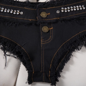 Dettaglio di pantaloncini di jeans neri con strass lucidi e orlo con frange e nappe
