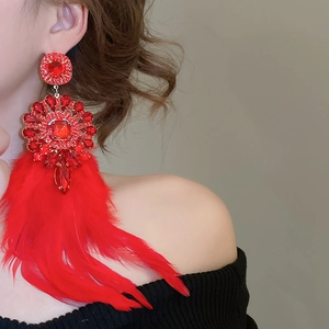 Détail de longues boucles d'oreilles en plumes rouges avec strass portées par un mannequin