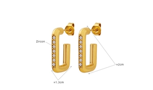 Détail de boucles d'oreilles géométriques dorées avec zircons blancs sertis verticalement