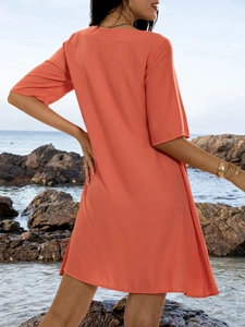 Detail of coral orange short-sleeved dress fabric texture in a coastal beach setting