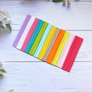 Set of 12 solid high-elastic yoga headbands in various colors on white wood background