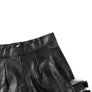 Dettaglio di pantaloncini in ecopelle nera con pieghe in vita e fibbia in metallo