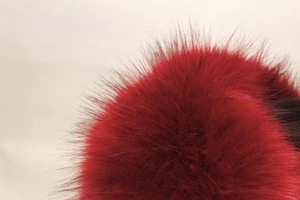 Détail de la texture en fausse fourrure rouge et noire sur un bonnet d'hiver pour femmes