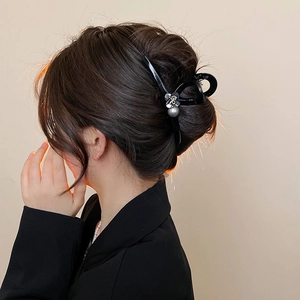 Detail of a large black hair claw clip with silver pearls and flowers on a model