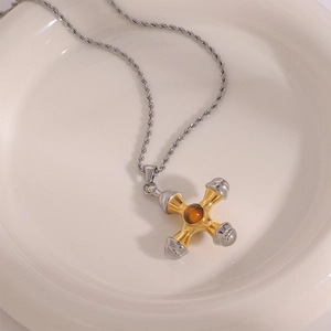 Détail macro du pendentif croix en acier bicolore avec incrustation de pierre d'ambre