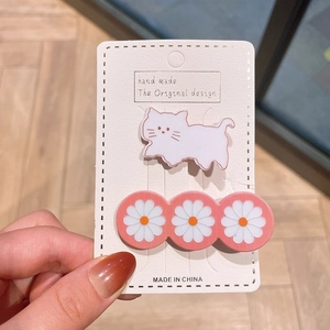 Detail of cute acrylic hair clips with white cat and pink daisy patterns for girls