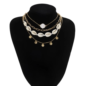 Detail of layered gold necklaces with shell and coin pendants on black neck model