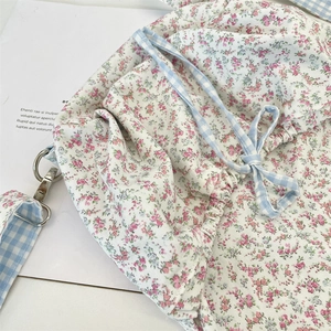 Detail of floral canvas bag with blue gingham straps and silver metal buckle