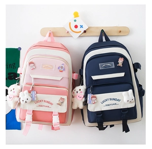 Close-up of school backpacks in pink and navy colors with cute bear charms and badges