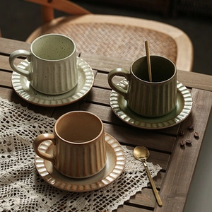 Ceramic coffee cup and saucer set with vertical stripes and speckled glaze on wood table