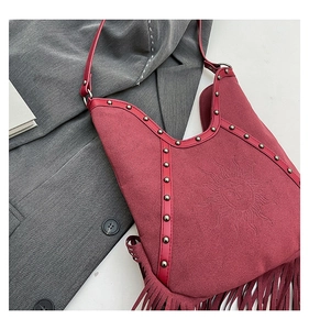 Detail of burgundy fringe bag with sun totem embossing and metallic rivets accents