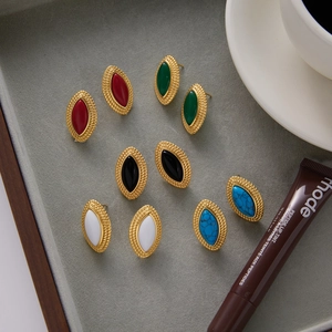 Flat lay of retro gold-finish marquise earrings with colorful inlay on gray velvet tray