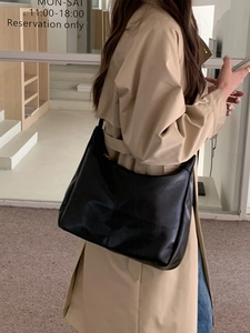 Minimalist black soft leather tote bag worn by a model in a modern urban setting