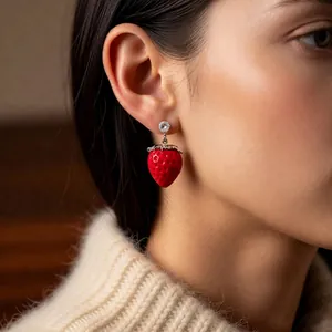 Vintage style red strawberry earrings with zircon studs worn by a model on casual outfit