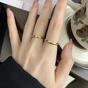 Close-up of minimalist gold-plated star and moon rings worn on hand with black nails