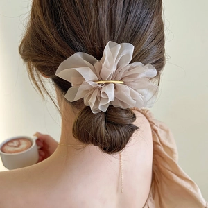 Detail of beige pleated fabric hair clip with gold metal bar on woman's hairstyle