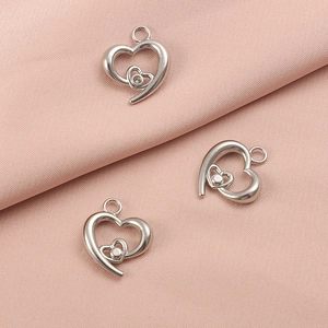 Three silver stainless steel hollow heart pendants with crystals on pink fabric