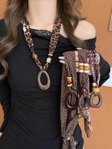 Close-up of bohemian fabric necklace with leopard print beads and large resin pendant