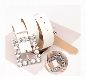 Detail view of a white leather belt featuring a large square rhinestone alloy buckle