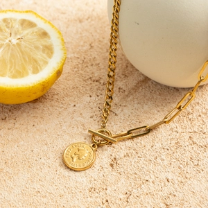 Detailed macro of golden portrait coin pendant and OT buckle on a mixed cuban chain