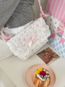Pink floral quilted crossbody bag with white lace trim and bow on lifestyle background