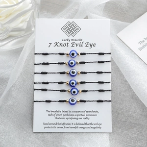 Set da 6 bracciali neri con 7 nodi, malocchio blu e perline dorate su scheda regalo