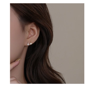 Close-up of minimalist gold and silver stud earrings with sparkling cubic zirconia on ears