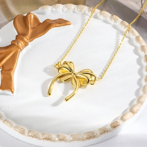 Macro shot of 18k gold plated bow pendant necklace on a decorative ceramic dish