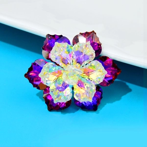 Elegant crystal flower brooch with purple and iridescent petals on a blue background