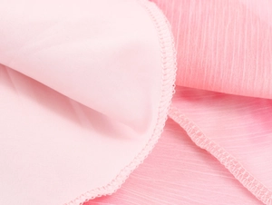Nahaufnahme des rosa Kleiderstoffs mit Rüschendetails und präziser Nahtverarbeitung
