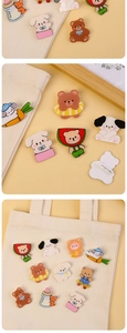 Close-up of cute acrylic animal brooches showing bear patterns on a canvas bag and desk