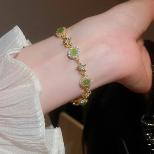 Close-up of vintage gold bracelet featuring green cat-eye stones and star-shaped zircon charms