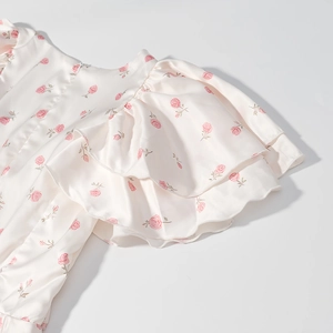 Détail de l'imprimé floral rose sur satin soyeux avec élégantes manches à double volant