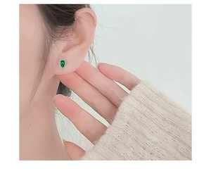 Macro shot of a teardrop-shaped green zircon stud earring in s925 silver on an ear