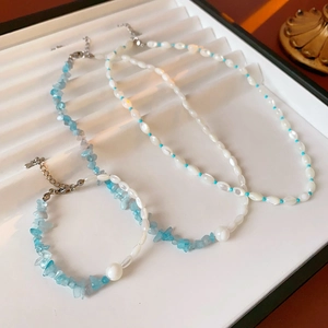 Detailed view of aquamarine and pearl necklaces with silver clasps on display tray