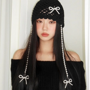 Close-up of black knitted beanie with elegant pearl bows and long hanging pearl pendants