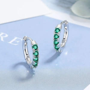 Macro detail of silver hoop earrings with pave set green cubic zirconia stones