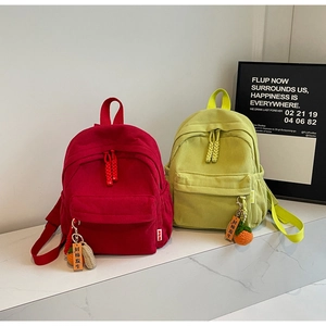 Close-up of corduroy texture on backpacks with knitted persimmon pendant and wooden charm