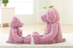 Detail of lavender plush teddy bears in two sizes with pink ribbons on a white rug