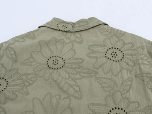 Detail of floral embroidery and hollow-out lace design on sage green cotton shirt