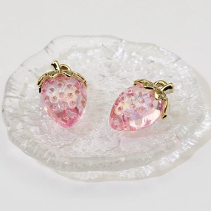 Pink transparent strawberry pendants with gold metal leaves on a glass plate decoration