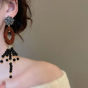 Close-up of ethnic beaded tassel earrings with brown resin oval and golden metal parts