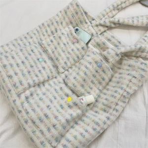 Detail of colorful striped plush tote bag with functional pockets and vibrant buttons