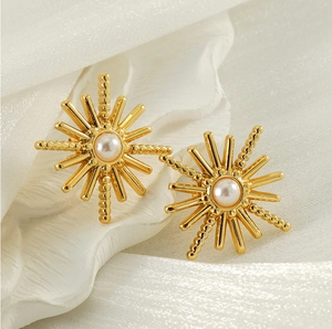 Détail macro de boucles d'oreilles perles soleil doré sur tissu en soie drapé