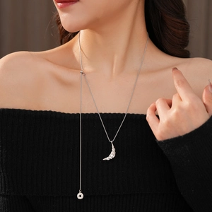 Detailed close-up of a silver crescent moon pendant necklace worn by a fashion model