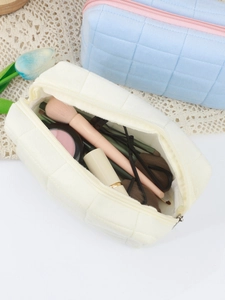 Macro view of checkered quilted velvet makeup bag interior filled with cosmetics