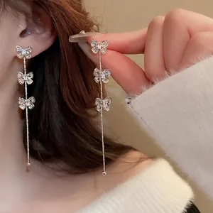 Boucles d'oreilles nœuds argentées avec zircons étincelants et longues franges