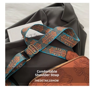 Detail of bohemian wide strap and embossed brown leather texture on a crossbody bag