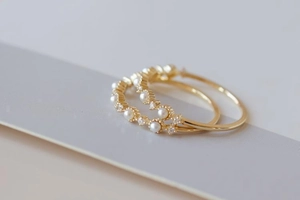 Macro detail of gold rings featuring minimalist pearls and delicate crystals for stacking
